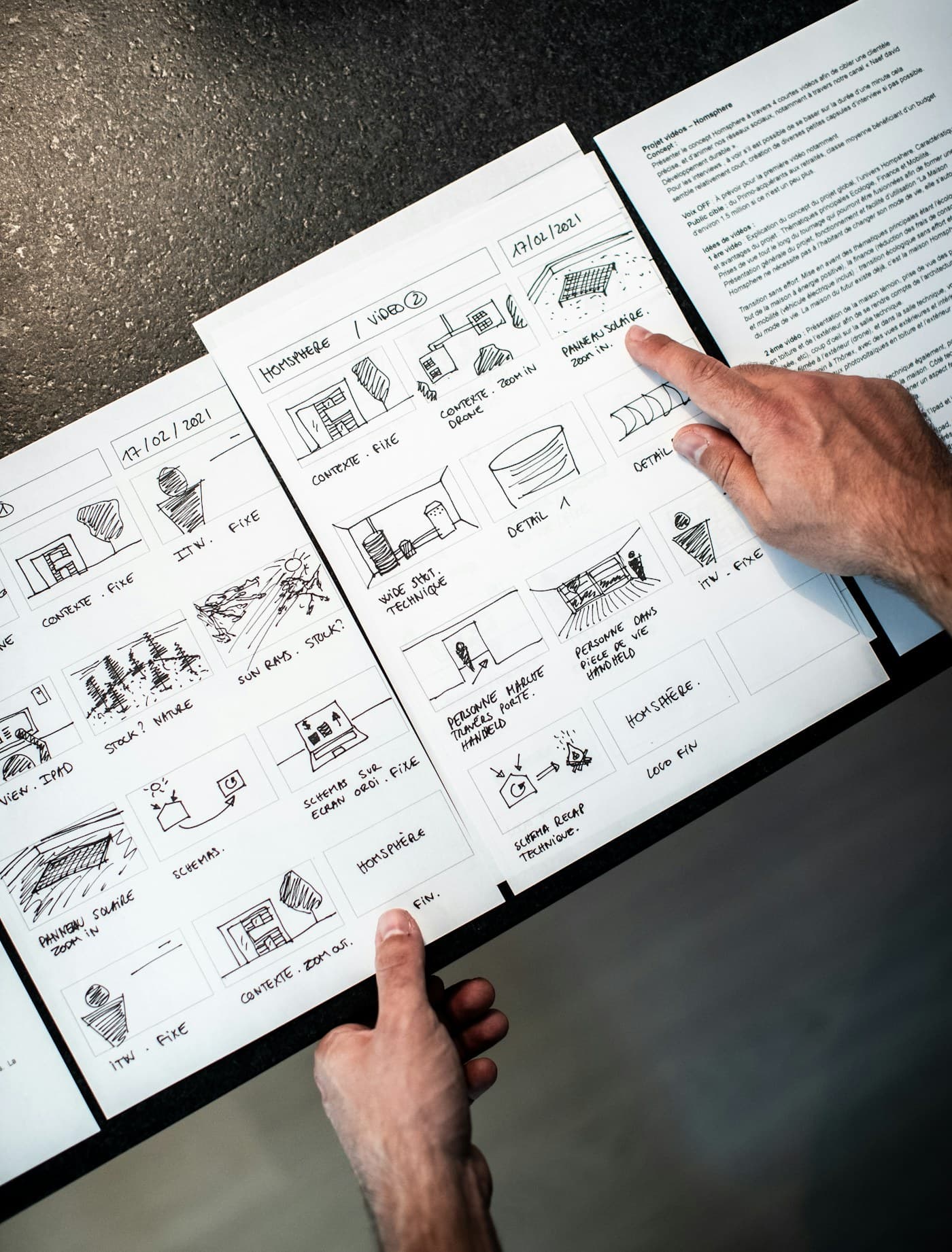 A hand turning the pages of a sketched storyboard